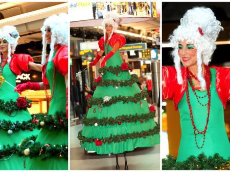 Betoverend kerstentertainment: Kerstboom Lady's Steltenlopers brengen magie met guirlandes en lampjes. Boek nu voor feestelijke sfeer!